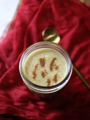 A glass jar with a spoon and cinnamon, ready to spice up your post-run nut butter smoothie.